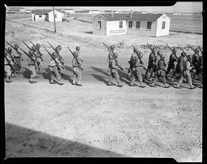 Soldiers marching in formation, buildings in background