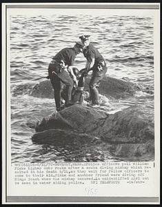 Police officers pull William Fiske higher onto rocks after a scuba diving mishap which resulted in his death 6/14, as they wait for fellow officers to come to their aid. Fiske and another friend were diving off Mingo Beach when the mishap occured. An unidentified girl can be seen in water aiding police.