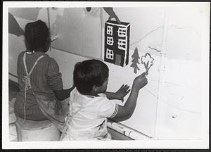 Girl and boy painting a mural on a wall