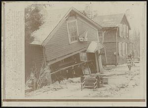 Flood Damage -- Furniture is strewn about the front yard of this partially collapsed house in Lee, Mass. after a flash flood roared through the town Sunday. The flood caused by the breaking of an earthen dam resulted in the death of at least one person.