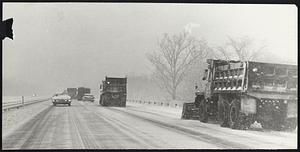Snowplows on Route 24, Brockton, early yesterday morning cleared heavily traveled highway. Rain later in day washed snow glaze off roads but increased danger of icing and flooding.