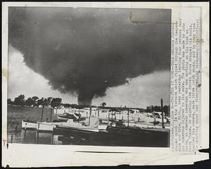 Twister at Work--This ominous funnel-shaped spout is the tornado which ripped through the temperence and Erie, Mich., area yesterday leaving four persons dead and numerous injured in its wake. The photo was made by John Burdo, an amateur camerman who was working on his boat at Point Place. On sighting the funnel Burdo dropped his tools, grabbed his camera, made three quick shots, and by that time the whirling spout had disappeared.1