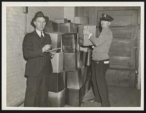 Patrolman Thom J. Lowndergan piling cans of alcohol as Patrolman Edw. J. Curtis of liquor squad checks