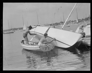Two yachtsmen washing hull of sailboat
