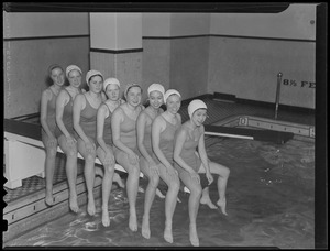 Women's swim team sitting on diving board