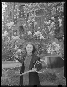 Woman poses with racket and flowering tree