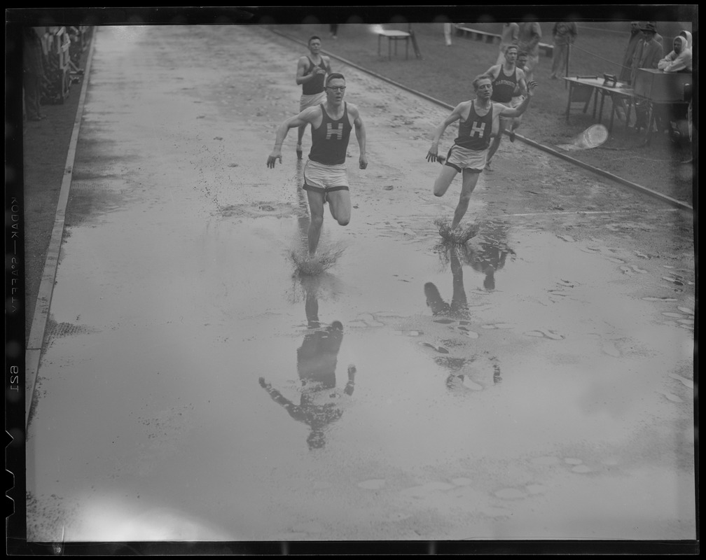 Splashing over the line in the 100 yard dash in Harvard Stadium, winner Bob Twitchell, left and Pete Dow, second, Harvard-Dartmouth meet