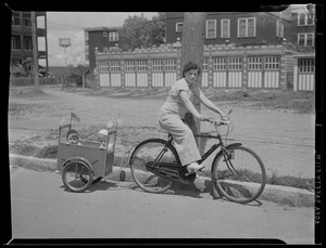 Bicycle - trailer arrangement allows Mrs. Oscar Rubillard of North Cambridge to take her children, Phillip, 1, and Rene, 2, with her when she goes shopping or for a spin. The youngsters love it.