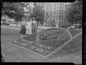 Three girls with flower bed spelling: "Mayor Tobin welcomes the Navy"