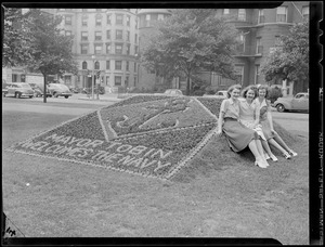 Three girls with flower bed spelling: "Mayor Tobin welcomes the Navy"