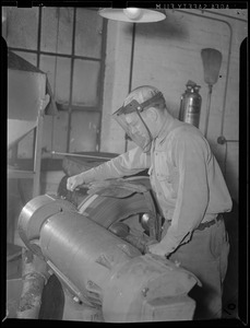WWII: Men wearing face shield working with a tire (for scrap)