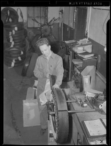 WWII: Man taking rubber off tire for scrap