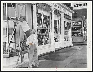 Taping windows of Columbus Ave. store to strengthen them against Hurricane Donna are Max Selver (on ladder), Belmont, and Sam Ruby, Brighton.