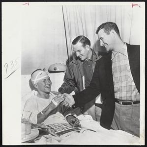 Smiling His Thanks is Eddie Thalacker, 14, of Westfield, Wis., as he receives a baseball from Milwaukee Braves players. They are first baseman Joe Adcock (right) and Del Rice, catcher (center). Presentation was made at Memorial Hospital, Waukesha, Wis. Eddie is one of 900 students who were en route to the Braves-Dodgers game when their train collided with a truck. Many were hospitalized.