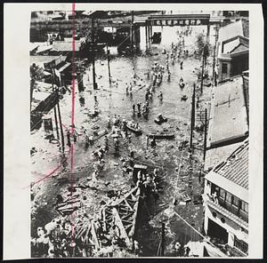 New Grief in Japan-Visited again by disaster, natives of Osaka, Japan, probe for salvageable belongings in the flooded industrial area of the southern Japanese city after a typhoon on Monday (Tokyo time) caused heavy loss of life and property damage on the island. Tentative estimates placed the number of dead as at least 109, and the injured at more than 1000.