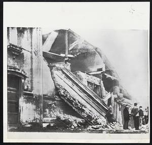 Series of severe earthquakes in Chile have taken heavy toll of persons and building. At left is main Catholic Church in Concepcion damaged after being rocked repeatedly. At right a soldier stands guard near electrical shop in some city.