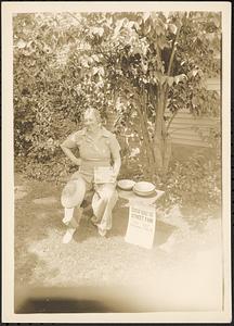 Woman seated with pies and poster