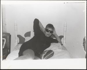 Young woman in sunglasses lounging on a bed