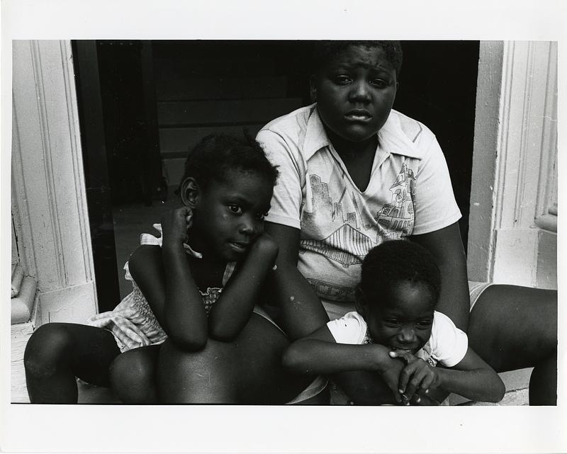 Portrait of a woman and two children sitting in a doorway