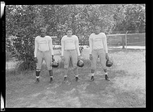 Three players of the Springfield College Football Team hold their helmets and pose for a picture
