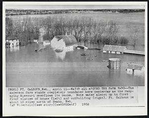 Water All Around the Farm Yard -- The Anderson farm stands completely inundated here yesterday as the rampaging Missouri overflows its banks. Note water almost up to first floor windows of house (left) and outbuilding (right). Ft. Calhoun is about 15 miles north of Omaha, Neb.