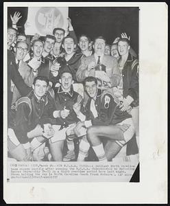 Win N.C.A.A. Title--A jubilant North Carolina team cheers lustily after winning the N.C.A.A. championship by defeating Kansas University 54-53 in a third overtime period here last night. Shown holding the cup is North Carolina Coach Frank McGuire.