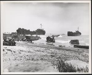 USS LST-344 at left, along with numerous LCVPs from transports anchored offshore, landing troops and equipment at Gela, Sicily