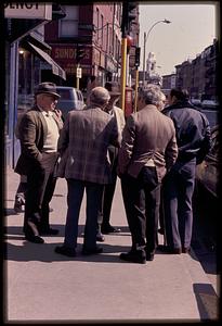 A group of men standing on the corner of Hanover and Parmenter Streets, North End, St. Stephen's in the far background