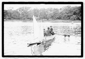 Men in a rowboat next to model sailboats