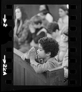Orphan boy prays at mass, Brighton