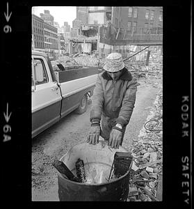 Demolition worker warms hands at oil-drum fire on winter day, Boston