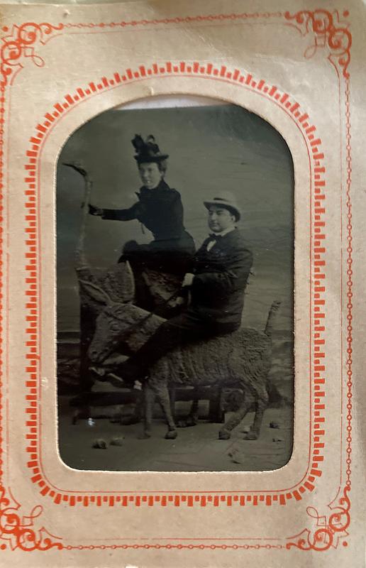 Unidentified man and woman posed on statues of animals