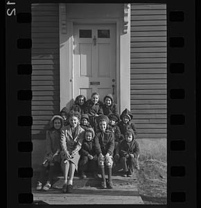 Children posing on front steps, possibly with a teacher