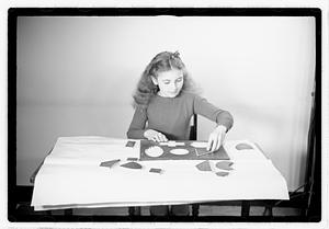 A girl matching fitting shapes in a puzzle