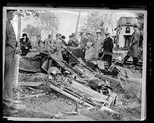 People gathered around a completely wrecked car