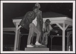 Two young people posing with a statue