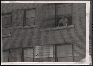 Man looking out a window of Newtowne Court and Washington Elms Maintenance office