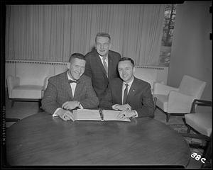 Three men looking at a binder