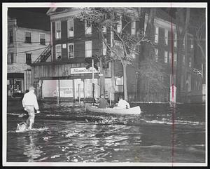 Canoe To The rescue-Two men swing swift paddles as they race to join convoy of small craft which aided marooned residents in Peabody.