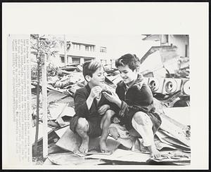 Lunching On American Candy -- This pile of rubble once was home for these two youngsters in the earthquake battered coastal town of Puerto Montt, Chile. Air Force men who brought emergency supplies to the town provided the candy. Military Air Transport Service planes also carried refugees to rehabilitation zones. The operation was called "Amigos Airlift".