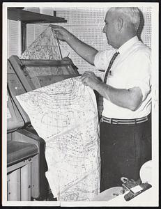 Weather Maps are checked by Hubert Hynes, aviation forecaster, as they come off the machines at the Boston Weather Bureau at the Boston Airport during the height of yesterday's hurricane Donna.