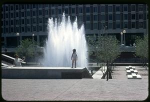 A girl standing at the Boston City Hall plaza fountain