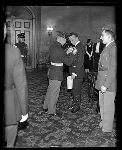 A man in uniform pinning something on another man's lapel
