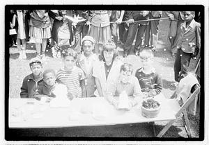 A group of children behind a collection of items