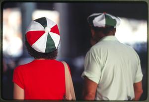 Boston - N. End 1981: A woman (L) wears a hat with the colors of the Italian flag as she walks near a man with a green and white hat