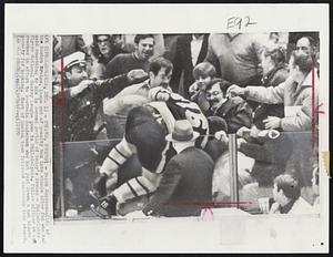 Philadelphia -- Temper, Temper! -- Derek Sanderson (16) of the Boston Bruins, leaps out of penalty box into stands after fan who had said something to him in second period of today's Bruins -- Philadelphia Flyers National Hockey League game in Philadelphia. Police officer at left reaches in effort to restrain Sanderson who had just drawn a two minute penalty for hooking. Most of Boston team followed Sanderson into stands.