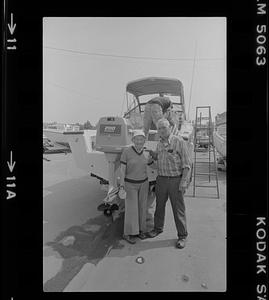 Russ Mingo and woman standing next to outboard motor of boat