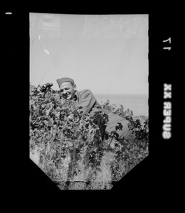 Warren Favor, of the U. S. Army's 649th Engineer Battalion, lying in brush with binoculars in Algeria