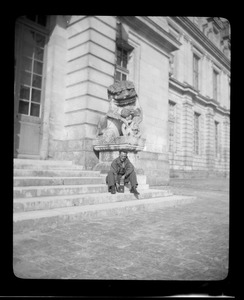 Warren Favor, of the U. S. Army's 649th Engineer Battalion, posing by stone lion, Palace of Fontainebleau, France