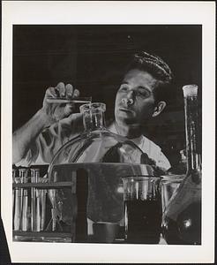 Dr. R. L. Tuve, above, chemist emptying test tube into a flask, conducts experiment which early in World War II led to discovery of shark repellent